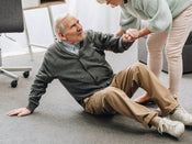 elderley gentleman being helped up after a fall. 