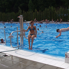 Woman being lowered into a swimming pool with people swimming in the background