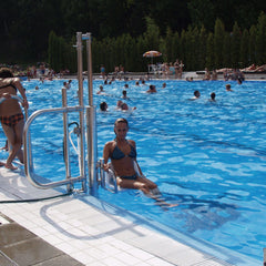 Woman being lowered into a swimming pool with people swimming in the background
