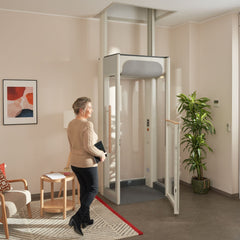 Woman standing in front of a home lift in a living room setting.