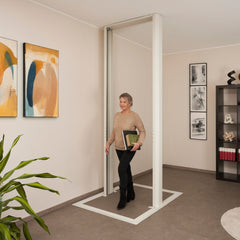 Woman standing in a stannah home lift, holding a black folder and green book